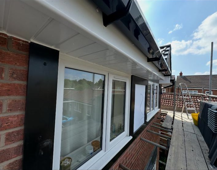 White soffit and fascia above bungalow windows, with scaffold boards